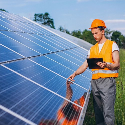 Uma instalação de usina fotovoltaica em um dia ensolarado, com o eletricista responsável em frente aos painéis solares, fazendo o comissionamento, créditos da imagem para: senivpetro no Freepik