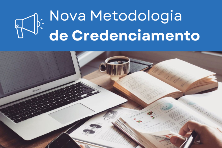 Essa imagem apresenta o texto: 'Nova Metodologia de Credenciamento FINAME' e mostra um MacBook Air com gráficos exibidos na tela. Na mesa, também há uma bela xícara de café, uma agenda e três livros abertos, com um deles sendo folheado por uma mão que segura uma caneta. No canto da imagem, é possível ver parte de um telefone celular.